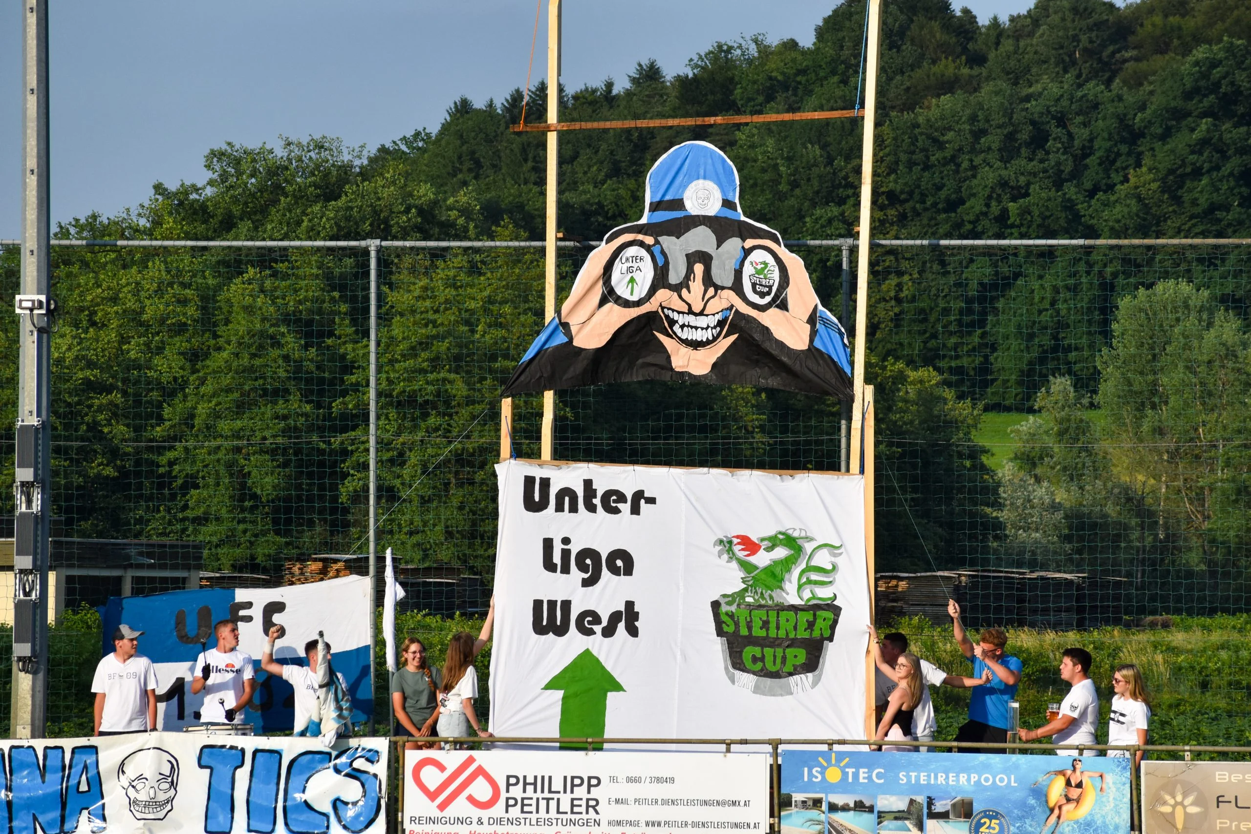 Choreo der Young Blue Fanatics: Figur mit Fernglas über dem Transparent „Unterliga West“